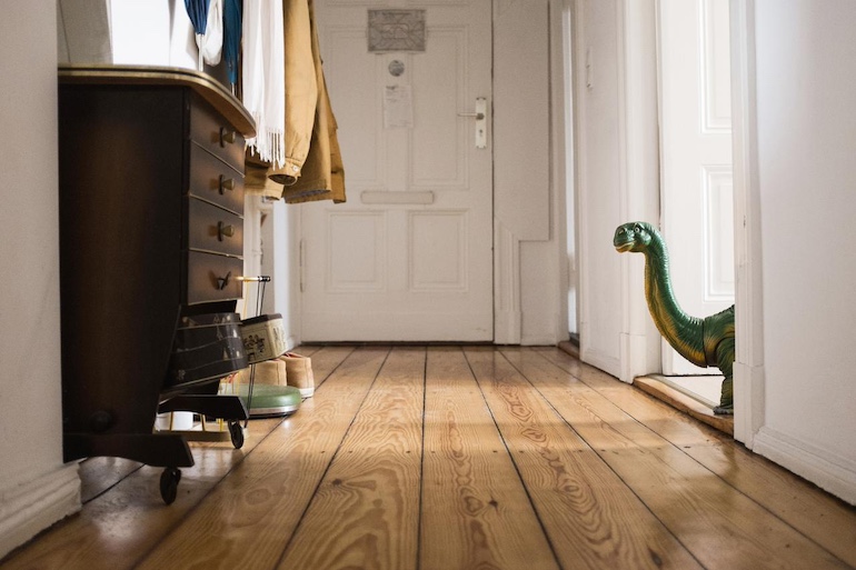 Immobilienverkauf: besser vermietet oder unvermietet verkaufen? Flur aus Froschperspektive, Dino schaut aus einem Raum heraus
